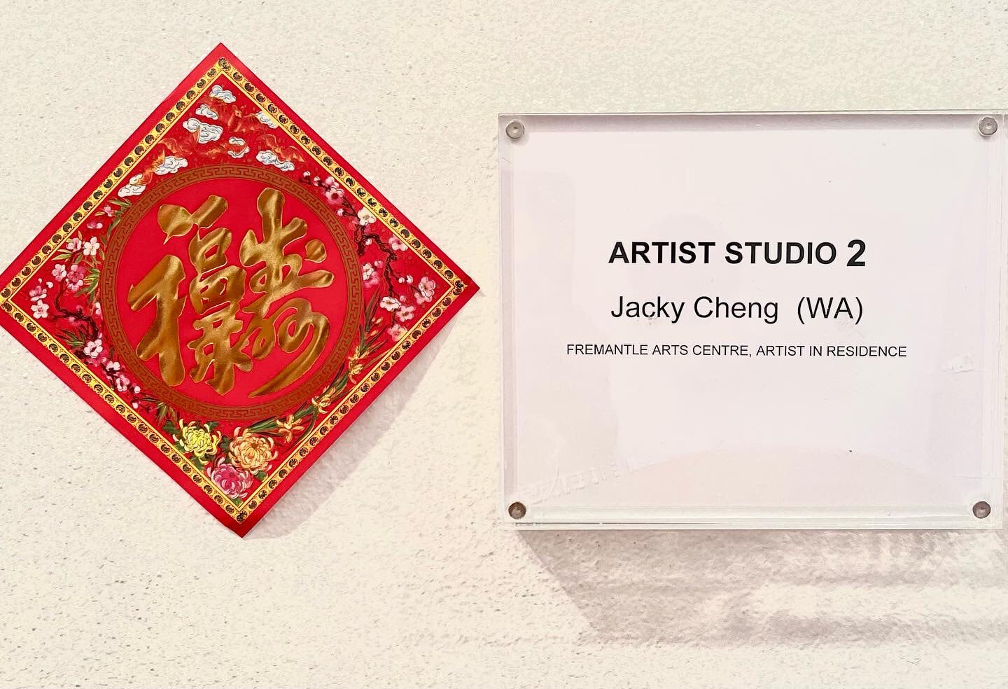 To the left, a chinese prosperity sticker with chinese character symbolises wealth and prosperity. To the right, name on wall - Jacky Cheng, Artist in Residence, Studio 2. 